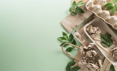Dünya Çevre Günü, yeşile dönün, geri dönüşüm, toprak günü ve eko konsepti, farklı kağıt atık malzemeleri ve pastel arka planda bitki.
