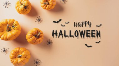 Pastel turuncu arka planda balkabağı ve siyah örümcekten yapılmış Cadılar Bayramı süslemeleri. Düz konum, metin için kopyalama alanı olan üst görünüm.