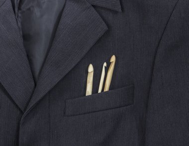 bir koyu siyah adamın ceketinin bir ışık şerit bir göğüs cebinde farklı boyutlarda ahşap kanca örgü yatıyordu