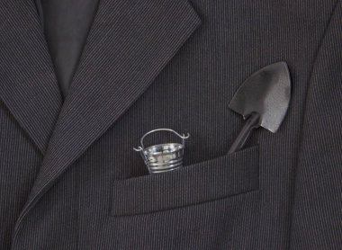 bir koyu siyah adamın ceketinin bir ışık şerit bir göğüs cebinde işte bir kova ve bir kürek