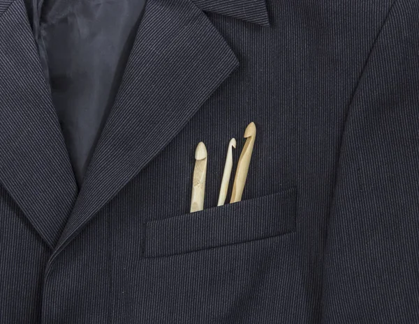 bir koyu siyah adamın ceketinin bir ışık şerit bir göğüs cebinde farklı boyutlarda ahşap kanca örgü yatıyordu