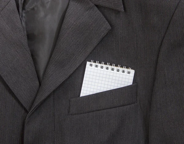 In de borstzak van een donkere zwarte man jas in een licht strip Leg een notitieblok op veren in een kooi — Stockfoto