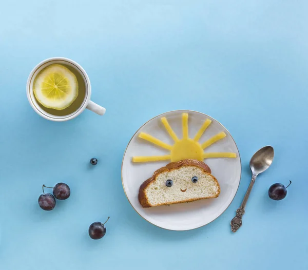 På blå bakgrund frukost morgonen sol moln glädje himlen strålar söt smörgås hälsosam mat bär blåbär plommon bröd ost tallrik sked som serverar servett kopp te dryck — Stockfoto