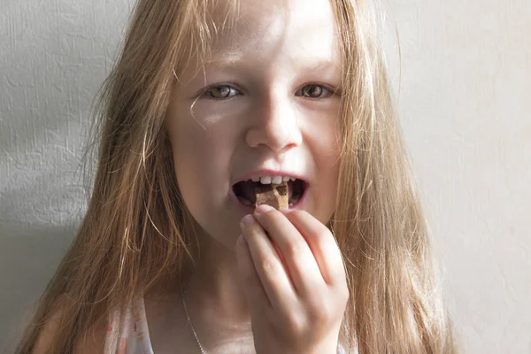 Σε λευκό φόντο το όμορφο κορίτσι με μακριά μαλλιά χαμογελώντας αυγή πρωί τρώει γλυκά — Φωτογραφία Αρχείου