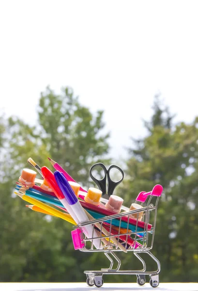 Em um contexto de árvores de bokeh verdes em um carrinho estudo de acessórios de artigos de papelaria multicores — Fotografia de Stock