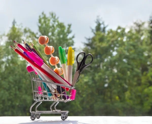 Em um contexto de árvores de bokeh verdes em um carrinho estudo de acessórios de artigos de papelaria multicores — Fotografia de Stock