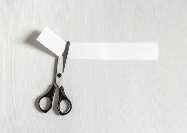 On a light background scissors cut off a piece of paper inscription — Stock Photo, Image