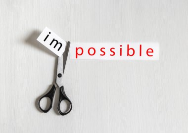on a light background a hand holds a pair of scissors cuts a piece of paper an inscription is impossible copy space clipart