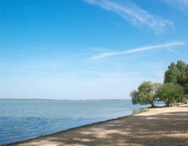 deniz kum plaj koyu mavi su gökyüzü ağaçlar sahilde
