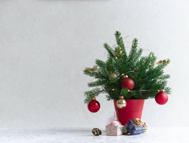 hafif bir arka plan üzerinde işte süslenmiş Noel ağacı altındaki kırmızı bir tencerede
