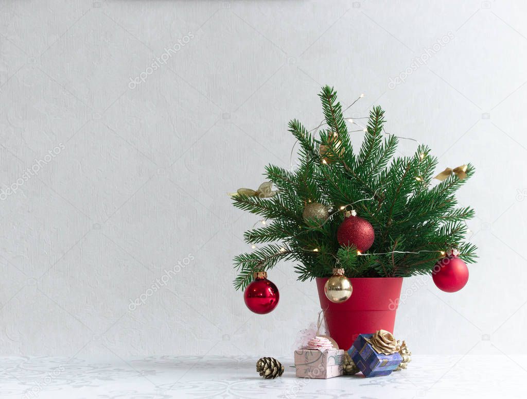 on a light background there is a Christmas decorated tree in a red pot under it