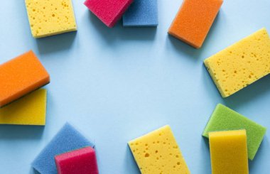 mavi bir arka plan üzerinde mutfak temizlik yemekleri temizlemek için farklı renk sünger bir düzen yatıyor