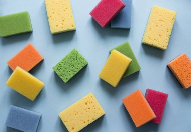 mavi bir arka plan üzerinde mutfak temizlik bulaşıkları düz yatıyordu temizlemek için farklı renk sünger bir düzen yatıyor