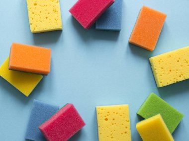 mavi bir arka plan üzerinde mutfak temizlik yemekleri temizlemek için farklı renk sünger bir düzen yatıyor