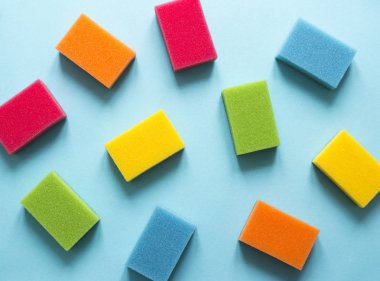 mavi bir arka plan üzerinde mutfak temizlik yemekleri flatlay temizlemek için farklı renk sünger bir düzen yatıyor