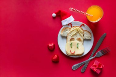 Kırmızı arka planda bir çocuk kahvaltısı var boğa ineğinde peynirli neşeli bir sandviç