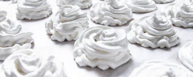 Beyaz pastel arka planda taze beyaz bir el yapımı marşmelov uzanıyor.  