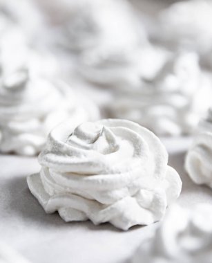 Beyaz pastel bir arka planda taze beyaz bir el yapımı marşmelov uzanıyor. Boşluğu kopyala, yumuşak odaklan