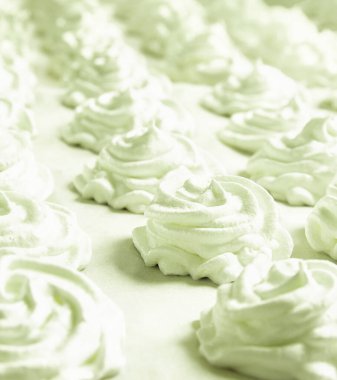 Yeşil bir pastel arka planda taze beyaz bir el yapımı marşmelov uzanıyor. Boşluğu kopyala 