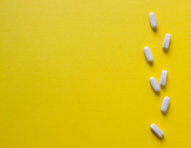 Sarı arkaplan vitamin tabletleri üzerinde 
