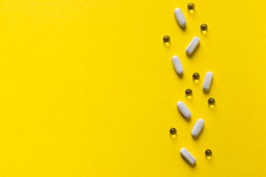 Sarı arkaplan vitamin tabletleri üzerinde 