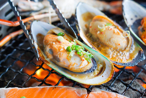 приготовленный моллюск на горячей угольной печи с щипцами
