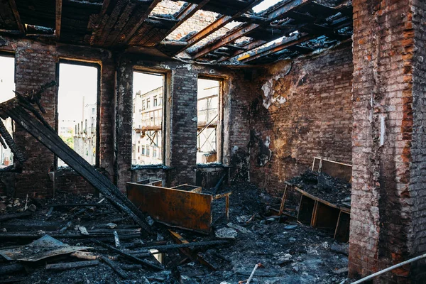 Ruins of burned brick house after fire disaster accident. Heaps of ash and arson, burnt furniture, collapsed roof