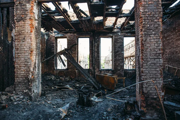 Ruins of burned brick house after fire disaster accident. Heaps of ash and arson, burnt furniture, collapsed roof, broken windows — Stock Photo, Image