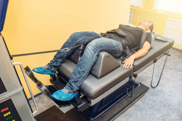Paciente masculino en tratamiento de discos intervertebrales y hernia espinal, estirando la columna vertebral en una máquina herramienta médica especial. Fisioterapia moderna —  Fotos de Stock