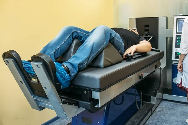 Male patient on treatment of intervertebral discs and spinal hernia, stretching spine on special medical machine tool. Modern physical therapy of neck, health care