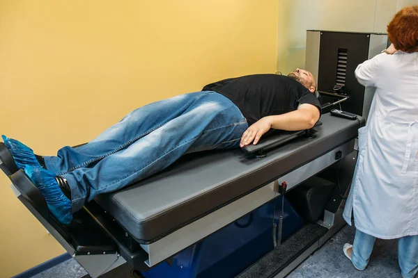Paciente masculino en tratamiento de discos intervertebrales y hernia espinal, estiramiento de la columna vertebral en una máquina herramienta médica especial —  Fotos de Stock