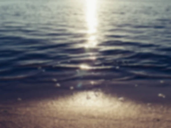 Sandstrand und Meereswelle im Sonnenuntergang, verschwommener abstrakter Sommerhintergrund — Stockfoto