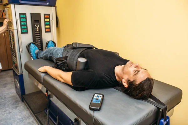 Man with problems of low back spinal hernia on stretching and decompression procedure in medical center, orthopedic therapy — Stock Image Man with problems of low back spinal hernia on stretching and decompression procedure in medical center, orthopedic therapy Stock Image