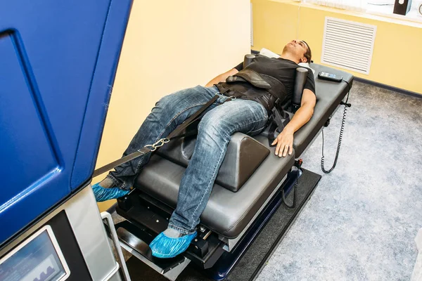 Man with problems of low back spinal hernia on stretching and decompression procedure in medical center, orthopedic therapy — Stock Image Man with problems of low back spinal hernia on stretching and decompression procedure in medical center, orthopedic therapy Royalty Free Stock Images