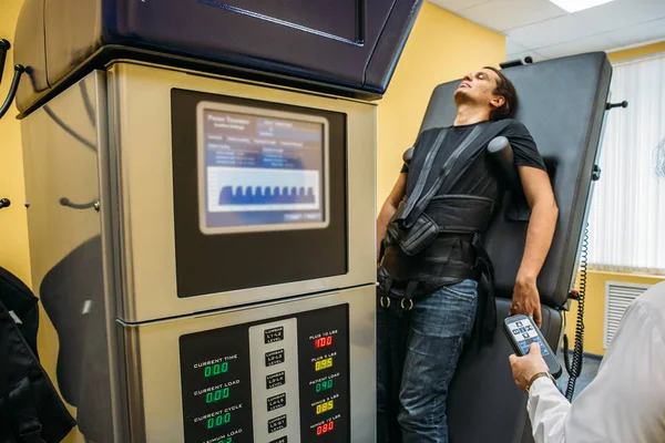Male patient at non-surgical treatment physiotherapy of lumbar spine and spinal cord dilatation in medical center on special medical equipment — Stock Image Male patient at non-surgical treatment physiotherapy of lumbar spine and spinal cord dilatation in medical center on special medical equipment Stock Image