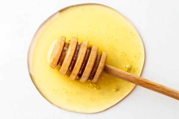 Gocciolatore di miele su fondo bianco con macchia di miele fresco biologico, macro, vista dall'alto — Foto Stock