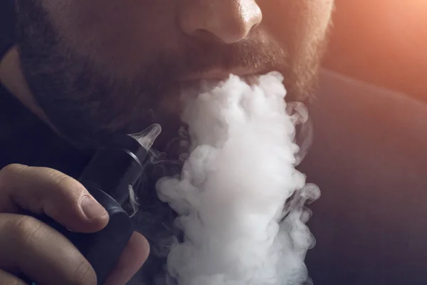 Ember vape e-cigaretta, e-folyadék, közelkép, lélegzik nagy felhő, gőz vagy pára. Vaping concept, fény hatása — Stock Fotó