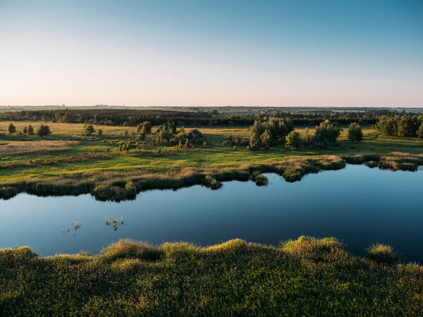 Flying above summer forest and lake at sunset on drone or aerostat, beautiful nature landscape panorama