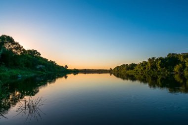 Yaz doğa panorama günbatımı, orman ağaçları ve nehir su, canlı yansıması ile sakin ve relax arka plan