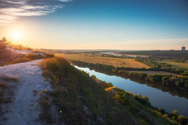 Bellissimo panorama paesaggistico naturale all'ora del tramonto. Vista dalla collina di gesso o montagna a prati verdi e campi con fiume e centrale nucleare lontano. Viaggio estivo sfondo tranquillo — Foto Stock