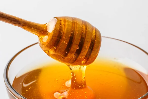 Honiglöffel mit Glasschale auf weißem Hintergrund Nahaufnahme, gesundes Bio-Naturprodukt — Stockfoto