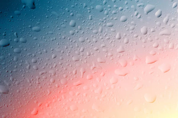 Gocce d'acqua sulla superficie del vetro della finestra con luce rossa e gialla — Foto Stock