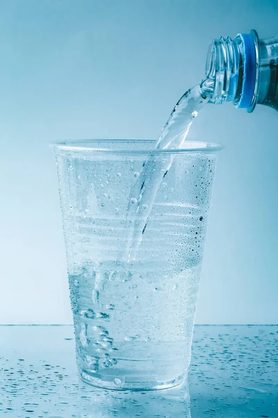 순수한 신선한 물 유리 또는 플라스틱 컵에서 가까이 건강 음료를 쏟아 — 스톡 사진