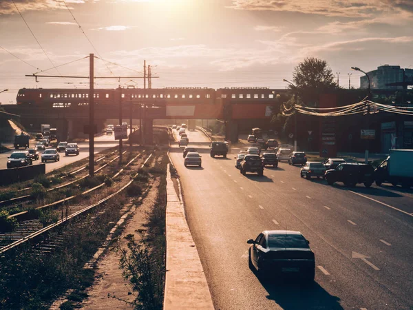 Stadtverkehr auf Asphaltstraße bei Sonnenuntergang, viele Autos fahren mit hoher Geschwindigkeit, verschwommenes Stadtbild — Stockfoto