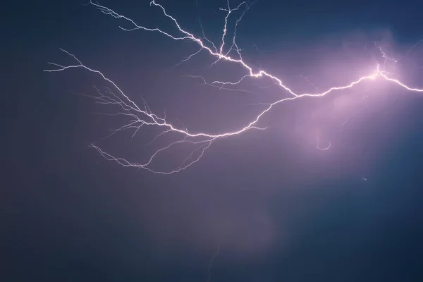 Heller Blitz vor dem Hintergrund eines dramatischen Nachthimmels mit Wolken, entladen atmosphärische Elektrizität in der Luft — Stockfoto