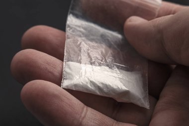 Palmiye Plastik paket kokain toz veya başka bir ilaç ile üzerinde tutan el mans. Yakın çekim