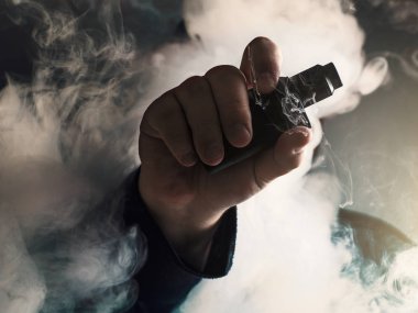 Adam el buharı arka plan bulut vape aygıtı gösterir. Vape kavramı