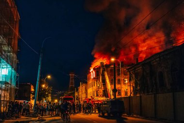 Apartman, alev ile itfaiye mücadele gece yangın siluetleri tanınmaz halde insanların etrafında durmak. Yangın felaketi ve kaza trajedi kavramı