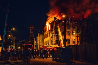 Apartman, alev ile itfaiye mücadele gece yangın siluetleri tanınmaz halde insanların etrafında durmak. Yangın felaketi ve kaza trajedi kavramı