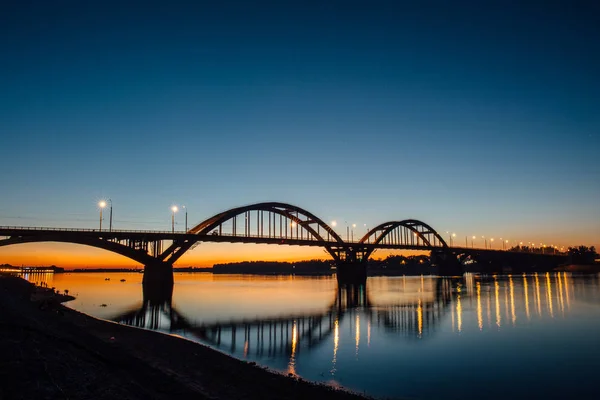 Volga bridge over Volga river after sunset with reflection in water, Yaroslavl region, Rybinsk city, Russia. Beautiful night landscape — Stock Photo, Image